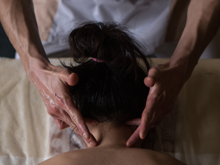Beautiful young woman reciving relxing Massage of Her Oiled Neck from Professional Masseur. Close upの写真素材