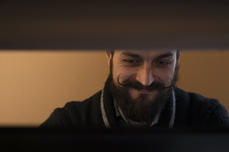 Modern, Expressive Bearded Office Clerk with Mustages Working with Notebook at Officeの写真素材