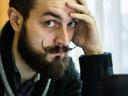 Modern, Expressive Bearded Office Clerk with Mustages Working with Notebook at Officeの写真素材