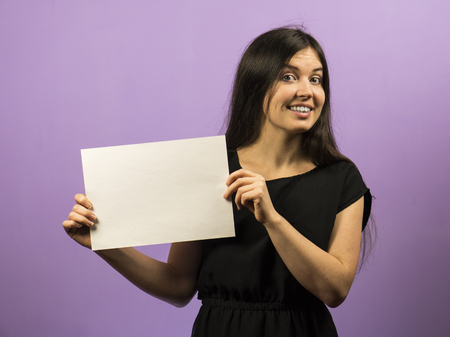 Young Brunette Girl Smiling and holding empty blank white board. Leaflet presentation.の写真素材