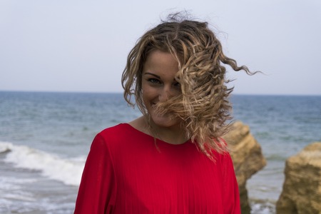 Happy Young Woman in Red Dress Have Fun at the Sea Coast Cliffの写真素材