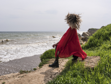 Happy Young Woman in Red Dress Have Fun at the Sea Coast Cliffの写真素材