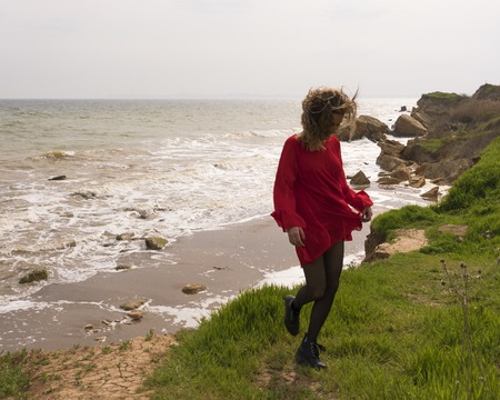 Happy Young Woman in Red Dress Have Fun at the Sea Coast Cliffの写真素材