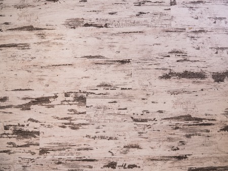Wooden wall with white paint is severely weathered and peeling