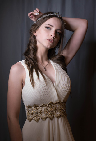Summer portrait of young beautiful lady wearing long white evening dress posing in the studio.の写真素材