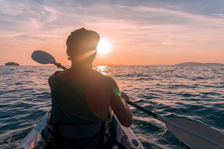 Kayaking. Man With kayak paddle at sunset sea Rowing to the Sun.の写真素材