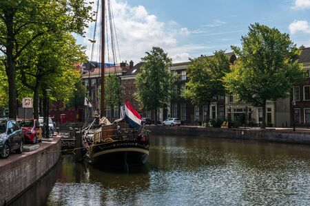 SCHIEDAM, NETHERLANDS - AUG 25: Traditional wooden sailing ship with flag and sign on a board in channel. Old historic harbor of Schiedam, The Netherlandsのeditorial素材