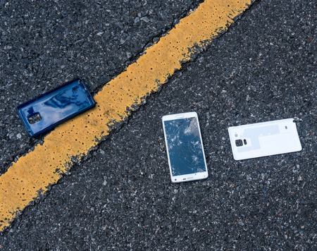Broken New Smartphone on asphalt road. Someone dropped device. Cracks on a big displayの写真素材