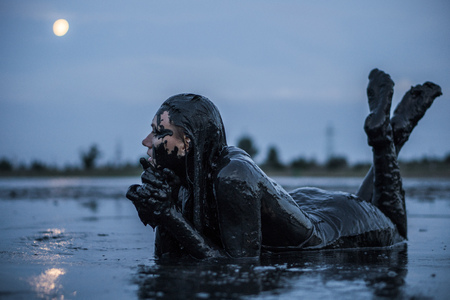 Adorable Slender Blonde Lays Smeared in a Black Healthy Mud looks like Petroleum Oilの写真素材