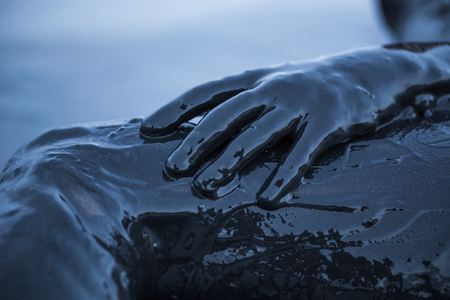 Close up hand of a girl Smeared in a black mud of a healthy salt Kuyalnik Firth in Odesa, Ukraine.の写真素材