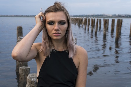 Portrait of Blonde Caucasian Girl in a Healthy Black Mud in old Firth with Wooden Posts for Salt Productionの写真素材
