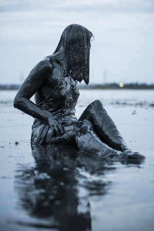 Portrait of an Adorable Caucasian Girl Sitting and posing Smeared with a Healthy Black Mud in old Firthの写真素材