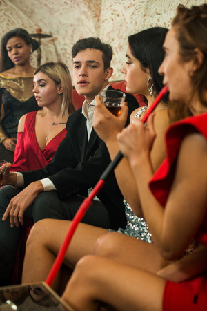 Group of young multi-ethnic friends relaxing in shisha club-bar in rich interiorの写真素材