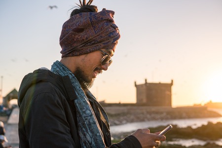 Young Asian Bearded Tourist man with Dreadlocks and scarf on head Having Fun in Essaouira, Morocco at the evening sunset timeの写真素材
