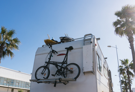 RV White Camper Car with bicycles on Road surrounded with Palm trees. Driving and cycling lifestyleの写真素材