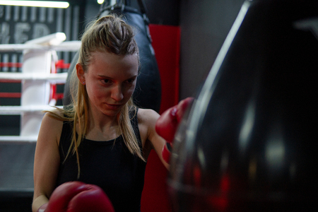 Blonde Caucasian fighter girl punching actively. Practicing in red Boxing Glovesの写真素材