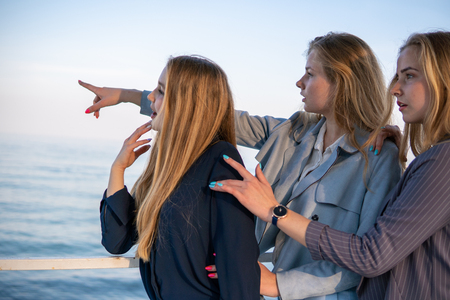 Three Beautiful teenage friends Girls Having fun near the sea. pointing somewhere far away with a fingerの写真素材