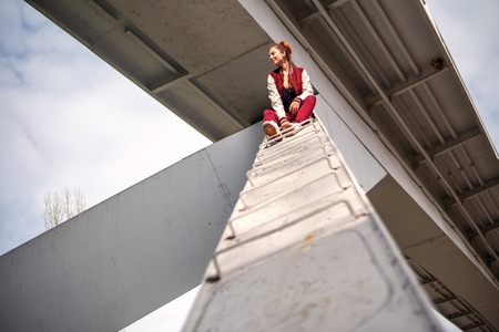 Dangerous trick. Young extremal fearless woman climb up under the bridge and having fun. Dangerous...