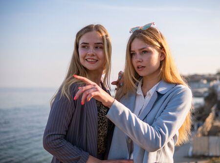 Two Twin teenage girls young woman laughting and having fun near the sea at sunset timeの写真素材