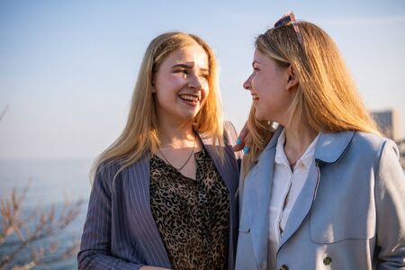 Two Twin teenage girls young woman laughing and having fun near the sea at sunset timeの写真素材