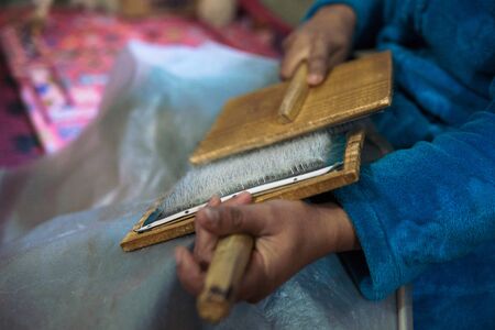 Woman with brushes preparing a wool for spining a woolen string for berber moroccan carpetsの写真素材