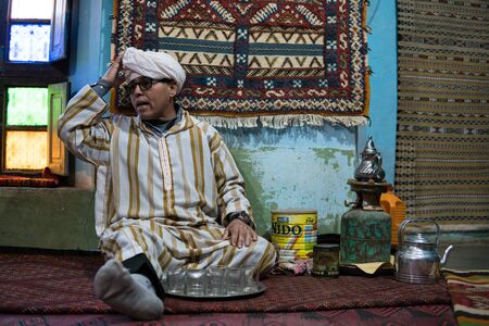 Tinerghir, Morocco - January 2019 : Berber man invites visitors in his house where produce carpets for a glass of traditional mint tea with wormwoodのeditorial素材
