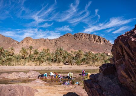 OURZAZATE, MOROCCO - JAN 2019: Berber women wash clothes in the river in beautiful picturesque place Oasis de Fint. Water day poor Moroccan tribesのeditorial素材
