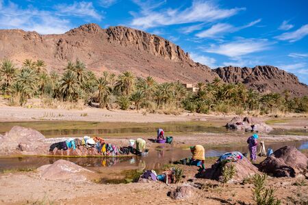 OURZAZATE, MOROCCO - JAN 2019: Berber women wash clothes in the river in beautiful picturesque place Oasis de Fint. Water day poor Moroccan tribesのeditorial素材