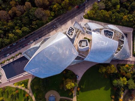 FRANCE, PARIS - OCT 2019: Aerial shot of Louis Vuitton Foundation museum modern building in Paris, France. Eiffel Tower on background, Boulogne forest around.のeditorial素材