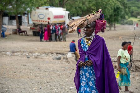 TANZANIA, MASAI VILLAGE - JANUARY 2020: woman with logs on the head in native masai village Engare Sero on the coast of Natron Lake in Maasailand, Arusha districtのeditorial素材
