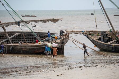 BAGAMOYO, TANZANIA - JANUARY 2020: local people fishermans on the big boat dhow in low tide....