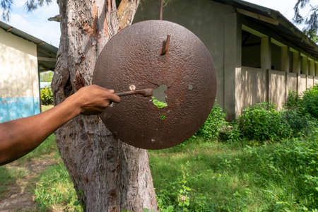 Rusty School Bell For Signalize about a School Brake Hanging on the Tree Near African school building in Primary School Yard in remote Africa Villageの写真素材
