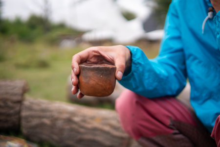 Drinking Chinese tea Pu Erh outdoor Near the Campfire Oven in Ecovillage. Clay tea pot, cup and pot on the little wooden tableの写真素材
