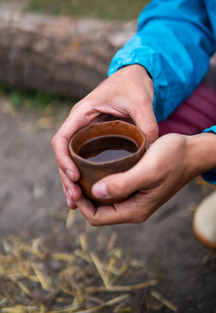 Drinking Chinese tea Pu Erh outdoor Near the Campfire Oven in Ecovillage. Clay tea pot, cup and pot on the little wooden tableの写真素材