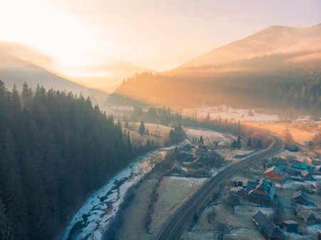 Mountain Village in the Morning. Aerial Shot of Majestic Sunrise in a Valley at Foggy Morning Mountains Landscape. Fir Tops and Cozy Houses in Carpathians, Tatariv, Ukraine, Europeの写真素材