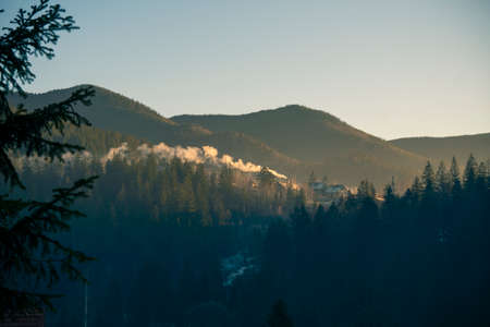 Cozy House in Mountains at Foggy Morning. Misty landscape in the mountains. Fantastic morning glowing by sunlightの写真素材
