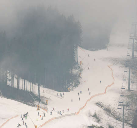 Skiing in the Fog Aerial View. Misty Low Season in Bukovel, the largest ski resort in Ukraine Carpathian Mountains. Slopes covered With Man-Made Snow at Warm Autumn Weatherの写真素材