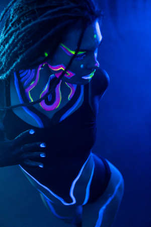 Cocky Girl with Dreadlocks in Ultraviolet neon light with Foggy Background. Bodyartの写真素材
