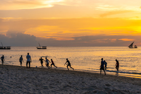 ZANZIBAR, TANZANIA - January 2020: African kids playing football on the beach at Nungwi village during sunset, Zanzibar, Tanzaniaのeditorial素材