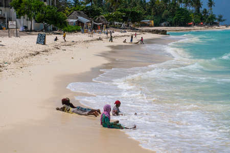 Nungwi, Zanzibar - December 2019: Boys and Girls in Turquoise Water. African children playing on the beach Ocean Surf Waves at Sunny Day at Nungwi village in northern Zanzibar, Tanzaniaのeditorial素材