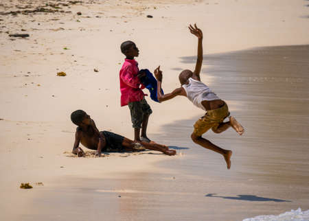 Nungwi, Zanzibar - December 2019: African children Boys playing on the beach Ocean Surf Waves at Sunny Day at Nungwi village in northern Zanzibar, Tanzaniaのeditorial素材