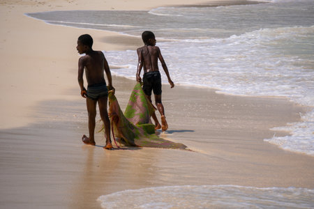 Nungwi, Zanzibar - December 2019: African children Boys playing on the beach Ocean Surf Waves at Sunny Day at Nungwi village in northern Zanzibar, Tanzaniaのeditorial素材