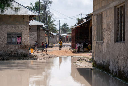 Zanzibar, Tanzania - JANUARY 2020: Black African People in their Usual Lifestyle on Streets with Paddles after rain in Zanzibar Villageのeditorial素材