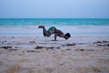 Young Attractive Muscular and Strong Athletic Black African Man at the White Sand Beach Training Body Calisthenicsの写真素材