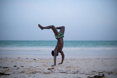 Young Attractive Muscular and Strong Athletic Black African Man at the White Sand Beach Training Body Calisthenicsの写真素材