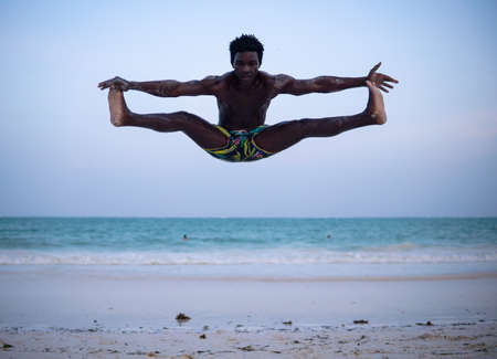 Young Attractive Muscular and Strong Athletic Black African Man at the White Sand Beach Training Body Calisthenicsの写真素材