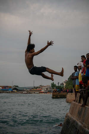 Stone Town, Zanzibar, Tanzania - January 2020: Locals run and jump into the sea From Stone Embarkment in Main City of Zanzibarのeditorial素材