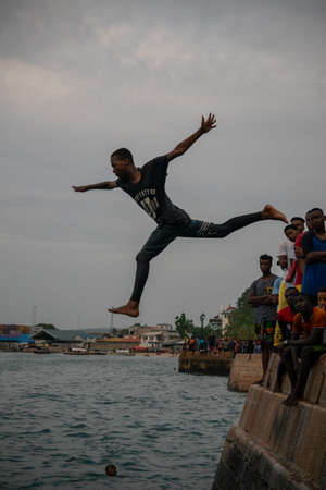 Stone Town, Zanzibar, Tanzania - January 2020: Locals run and jump into the sea From Stone Embarkment in Main City of Zanzibarのeditorial素材