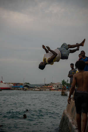 Stone Town, Zanzibar, Tanzania - January 2020: Locals run and jump into the sea From Stone Embarkment in Main City of Zanzibarのeditorial素材