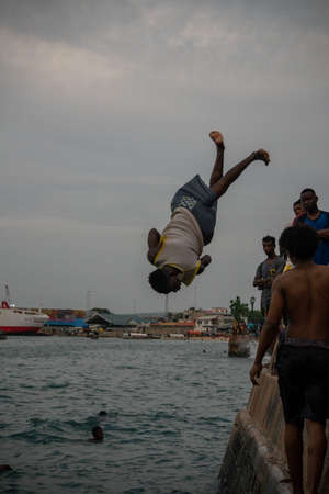 Stone Town, Zanzibar, Tanzania - January 2020: Locals run and jump into the sea From Stone Embarkment in Main City of Zanzibarのeditorial素材